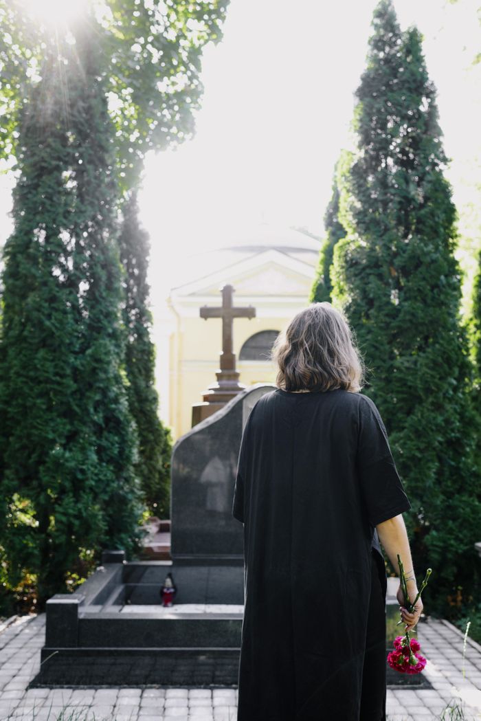 core-values A woman stands in contemplation at a peaceful cemetery, surrounded by trees.